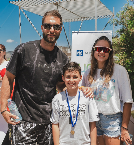 Αθλητής με νεαρή κοπέλα και αγόρι που φοράει μετάλλιο, από πίσω λογότυπο της Alpha Bank.