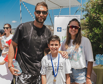 Αθλητής με νεαρή κοπέλα και αγόρι που φοράει μετάλλιο, από πίσω λογότυπο της Alpha Bank.
