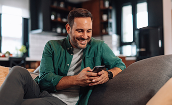 Άντρας που κοιτάει κάτι στο κινητό του και χαμογελάει